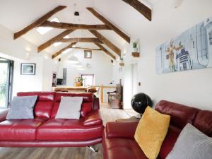 a living room with a red leather couch and a table at The Cart House in Liskeard