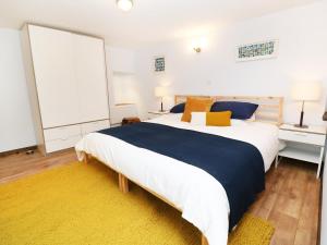 a bedroom with a large bed and a yellow rug at The Cart House in Liskeard