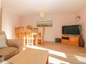 a living room with a couch and a tv and a table at Bearscombe in Ivybridge