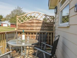 a table and chairs on a balcony with a wine bottle at Chalet 186 in Padstow