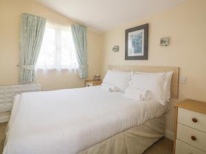 a bedroom with a large white bed with a window at Chalet 186 in Padstow
