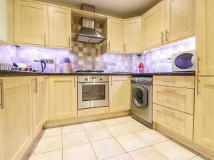 a kitchen with wooden cabinets and a washer and dryer at 4 Old Mill Court in Brixham
