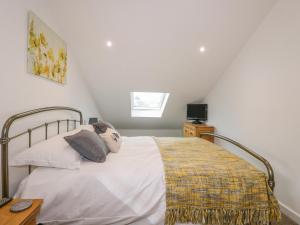 a bedroom with a bed with white sheets and a window at Coney Garth Cottage in Beckermet