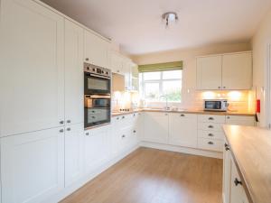 a white kitchen with white cabinets and a wooden floor at Bower View in Hereford