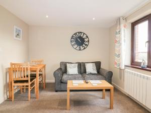 a living room with a couch and a table and a clock at Little May in Newquay