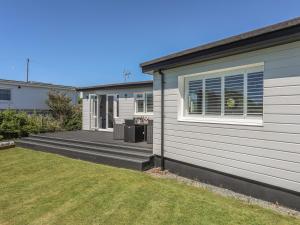 a house with a wooden deck next to a yard at Gadlys in Trearddur