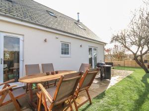 a patio with a wooden table and chairs and a grill at Kober House in Helston