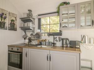 a kitchen with white cabinets and a sink at High Rigg Shepherd's Delight in Brampton
