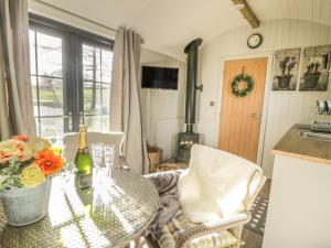 a kitchen with a table with a bottle of wine and flowers at High Rigg Shepherd's Delight in Brampton