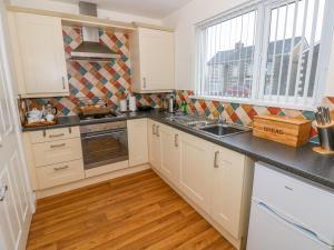 a kitchen with white cabinets and black counter tops at Ty Cerrig in Ammanford