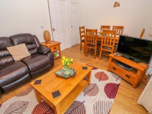 sala de estar con sofá de cuero y mesa en Ty Cerrig en Ammanford