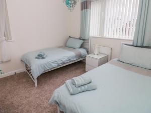 um pequeno quarto com 2 camas e uma janela em Ty Cerrig em Ammanford