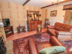 a living room with a couch and a television at Holly Cottage in Alnwick