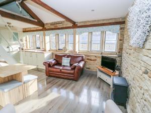 a living room with a leather couch and a television at Riverview Cottage in Holmfirth