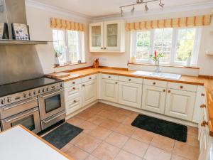 a kitchen with white cabinets and a stove top oven at Cheriton Villa in Tenby +8 photos