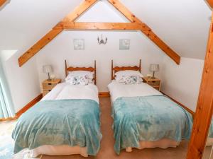 two twin beds in a attic bedroom with wooden beams at Cheriton Villa in Tenby