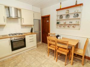 a kitchen with a table and chairs and a stove at Old Codgers Cottage in Windermere