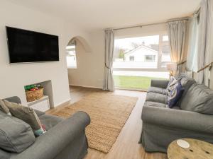 a living room with two couches and a flat screen tv at Ty Taid in Rhosneigr