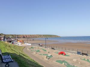 a view of a beach with a park and a bench at Bayside Cottage in Filey