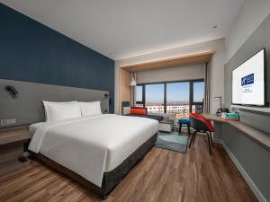 長春市にあるHoliday Inn Express Changchun Jingyue, an IHG Hotelのベッドとデスクが備わるホテルルームです。