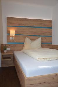 a bedroom with a bed with a wooden headboard at Platzwirt in Unterschneidheim