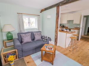 a living room with a blue couch and a kitchen at Wigrams Canalside Cottage in Southam