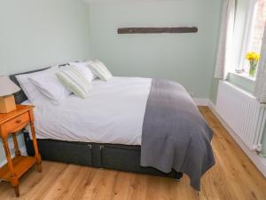 a bedroom with a bed with white sheets and pillows at Wigrams Canalside Cottage in Southam