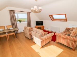 a living room with two chairs and a television at Llain Haf in Llangefni