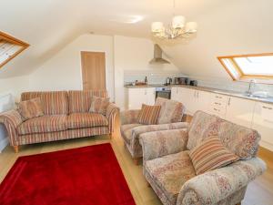 a living room with two couches and a red rug at Llain Haf in Llangefni