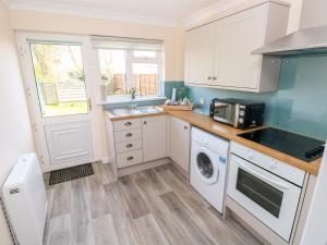 a kitchen with a sink and a washing machine at Cranford Cottage in Pembroke