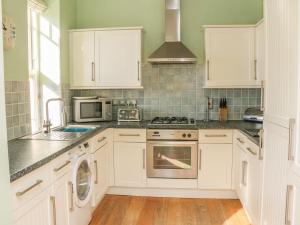 a kitchen with white cabinets and a stove top oven at Hartland View in Woolacombe