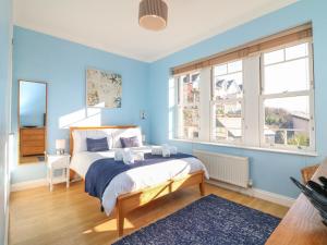 a bedroom with a bed with blue walls and windows at Hartland View in Woolacombe
