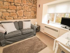 a living room with a couch and a stone wall at Robin Cottage in Morpeth