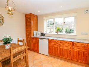 a kitchen with wooden cabinets and a table and a window at Rose Cottage in Darlington +18 photos
