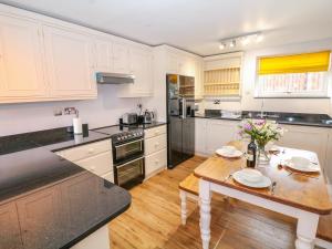 una cucina con mobili bianchi e un tavolo di legno di Monk's Cottage a Buxton