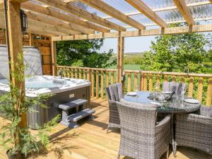 a deck with a hot tub and a table and chairs at Elm Lodge in Watchet