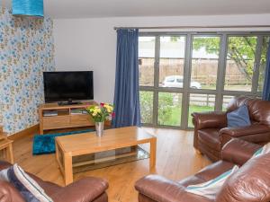 a living room with couches and a television and a table at Walnut Cottage in Newton Abbot