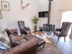 a living room with a leather couch and chairs and a fireplace at Clwyd Cottage in St Asaph