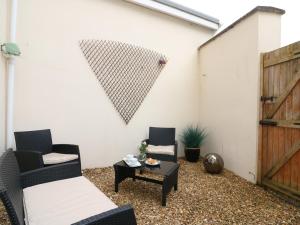 a patio with two chairs and a table and a wall at 10 Cove View in Ilfracombe