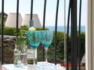 a table with two glasses and a vase with flowers at 10 Cove View in Ilfracombe