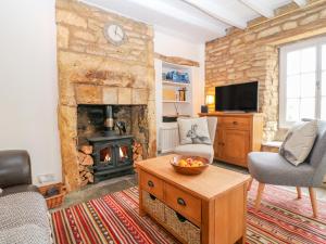 a living room with a stone wall with a fireplace at Thrower's Cottage in Blockley