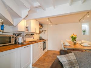 a kitchen with white cabinets and a table at Thrower's Cottage in Blockley +24 photos