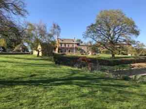 a house on a green field with trees and grass at Thrower's Cottage in Blockley