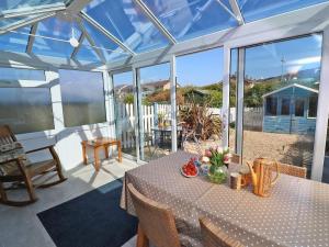 a conservatory with a table with flowers on it at Pebble Cottage in Redruth