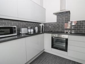 a kitchen with white cabinets and a microwave at Angel by the Sea in Bridlington