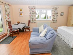 a living room with a blue couch and a bed at Bretton Mount Studio Flat in Eyam