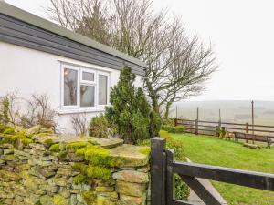 a house with a stone wall and a fence at Bretton Mount Studio Flat in Eyam