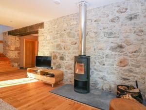 a living room with a stone wall with a wood stove at Boat House in Invergarry