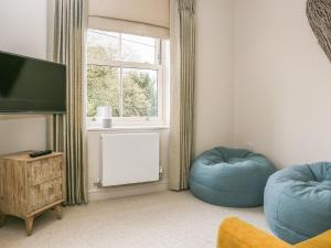 a living room with two blue ottomans and a window at Poets Corner in Bourton on the Water