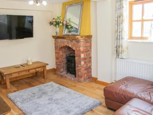 a living room with a brick fireplace with a mirror at Old Hall Barn 2 in Church Stretton